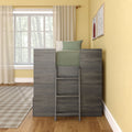 Modern children's loft bed with gray wooden ladder, green bedding, large window with sheer curtains, yellow walls and framed artwork