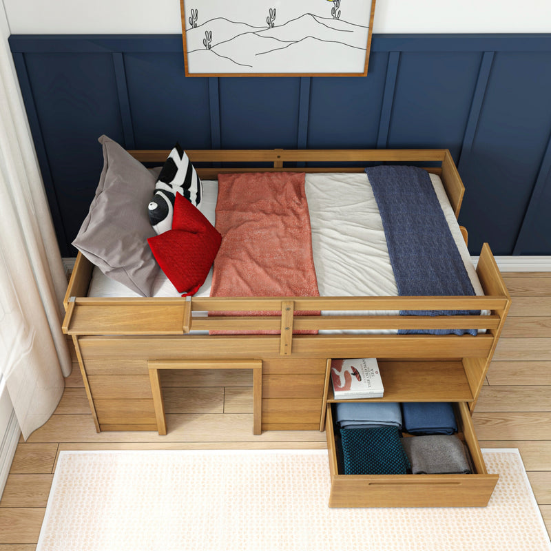 Wooden kid's bed with storage drawers and colorful bedding against a blue paneled wall.