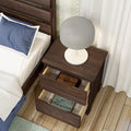 Modern walnut nightstand bedside table with white globe lamp and two open drawers revealing books beside an upholstered bed on hardwood floors