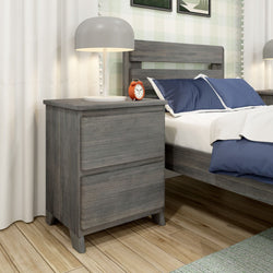 Modern wooden bedside table with lamp and alarm clock next to a bed with blue pillows.