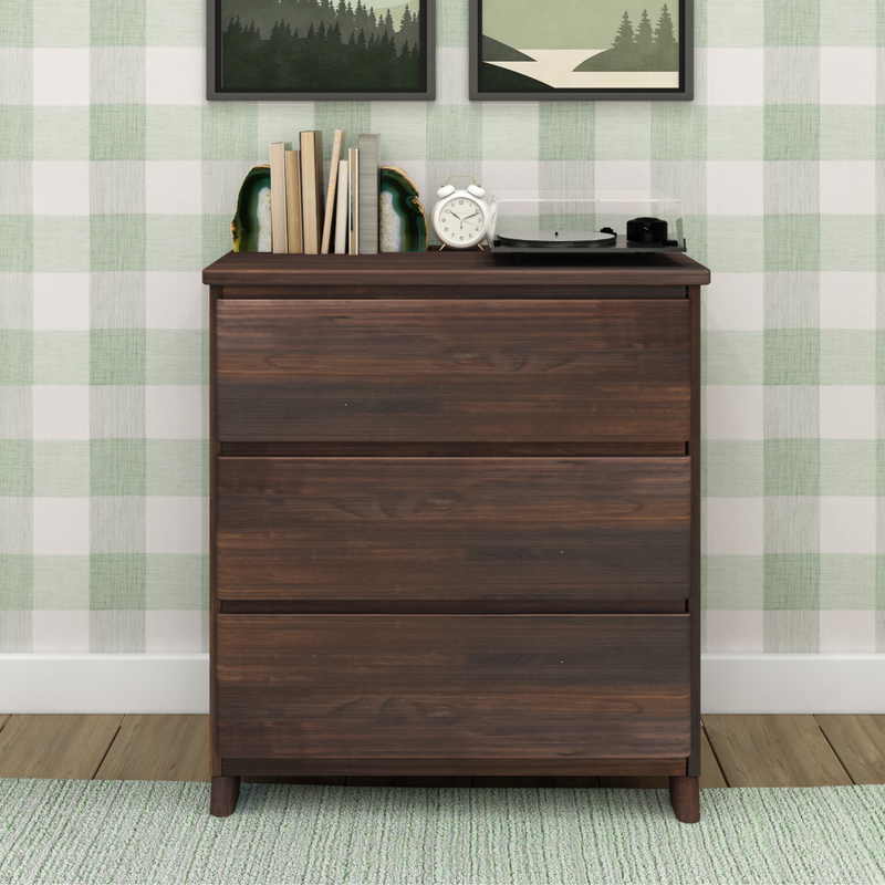 Dark wood dresser with modern design, featuring books, a clock, and a record player on top, set against a green checkered wall in a cozy room.