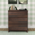 Mid-century modern dark wood dresser with vinyl record player, white alarm clock, stacked books and agate bookends against green plaid wallpaper