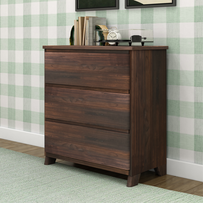 Wooden three-drawer dresser in a bedroom setting with decorative items on top.