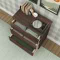 Top-down view of a mid-century modern dark wood dresser with three open drawers holding folded blankets and linens, a vinyl turntable, books and alarm clock on top, green plaid wallpaper and light green rug in a cozy bedroom setting
