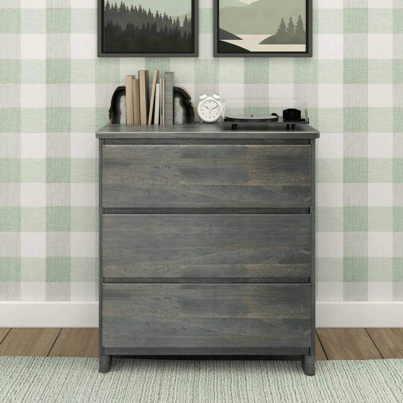 Wooden dresser with books and decor in a checkered wallpaper room.