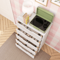 Green portable record player on white dresser with lamp and books in pink checkered nursery, open drawers with blankets