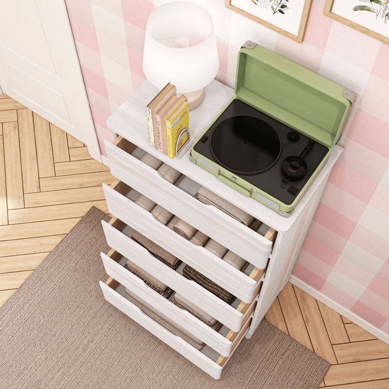 Green portable record player on white dresser with lamp and books in pink checkered nursery, open drawers with blankets