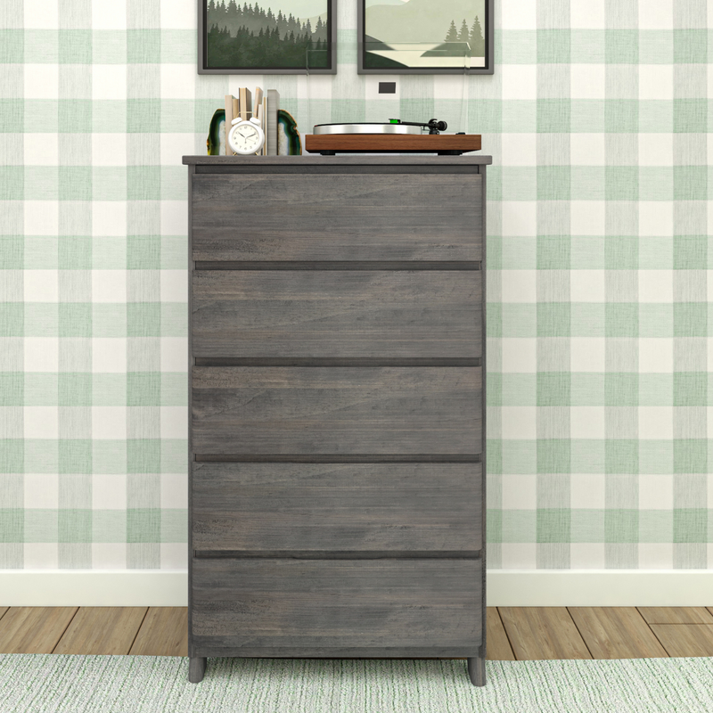 Gray wooden dresser with five drawers in a stylish modern room with checkered wallpaper, adorned with a clock and a record player on top.