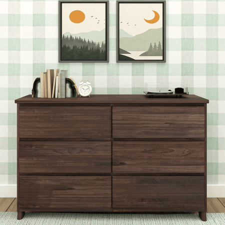 Dark wood dresser with books, clock, and turntable against plaid wallpaper with landscape art.