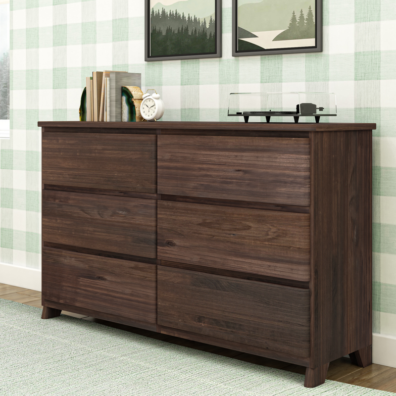 Wooden six-drawer dresser in modern bedroom with plaid wallpaper and decorative plants on top.