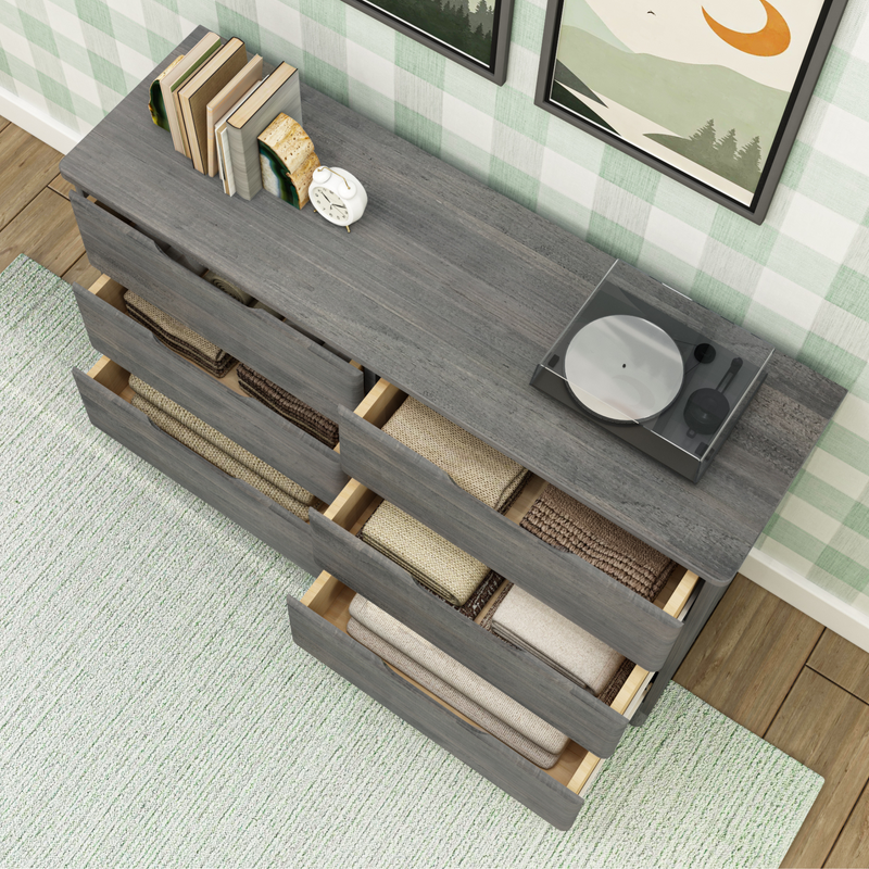 Gray wooden dresser with open drawers showing neatly folded clothes, books, a clock, and a record player on top; home decor and storage solution.