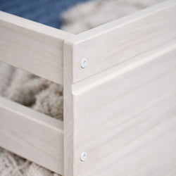Light wood bed frame corner close-up showing screw fasteners and natural wood grain on a neutral rug