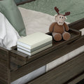 Plush moose toy on wooden bed tray with stacked books and green bedding — cozy kids bedroom or nursery decor