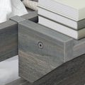 Close-up of gray weathered wooden platform bed frame corner with metal bracket and stacked hardcover books, modern rustic bedroom decor detail