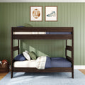 Dark wood bunk bed in kids' bedroom with green paneled wall, blue bedding, plaid pillows, framed football and cleat prints, and wicker basket of sports balls