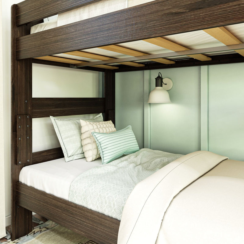 Close-up of dark wood bunk bed frame and slats with mint green pillows, quilted bedding, and white wall sconce in a modern bedroom