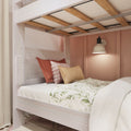 Loft bunk bed with whitewashed wood frame and exposed wooden slats, pink accent wall, industrial wall sconce, layered decorative pillows and floral duvet