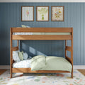 Wooden bunk bed with pastel green bedding and floral sheets against a blue vertical paneled wall, three framed floral prints above and floral rug in a cozy kids' bedroom