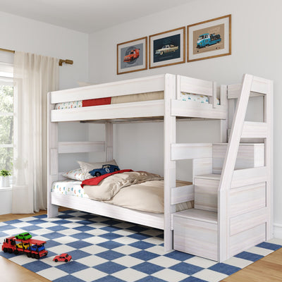 White wooden kids' bunk bed with built-in stairs, car-themed bedding and framed posters in a bright bedroom with blue checkered rug and toy cars