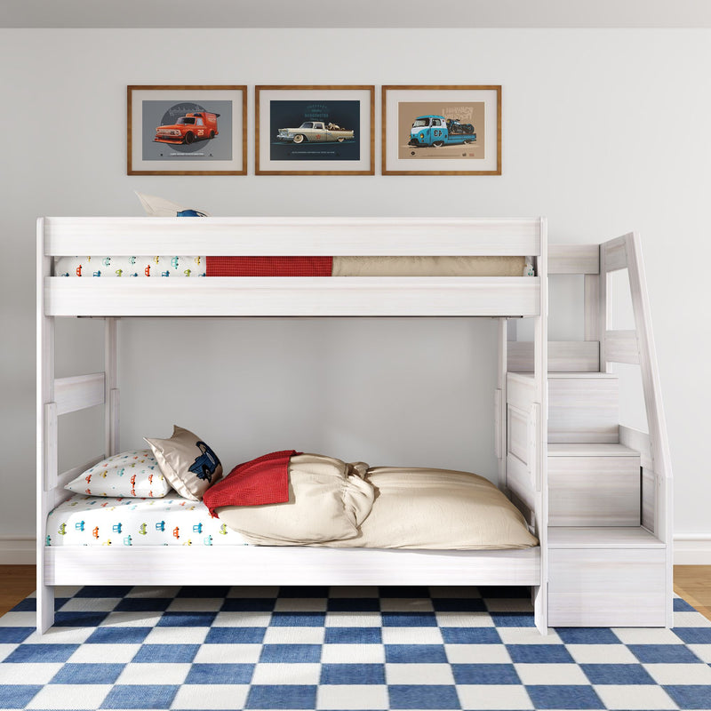 White wooden twin-over-twin bunk bed with built-in stairs in kids' bedroom, car-themed bedding, vintage car wall art and blue checkered rug