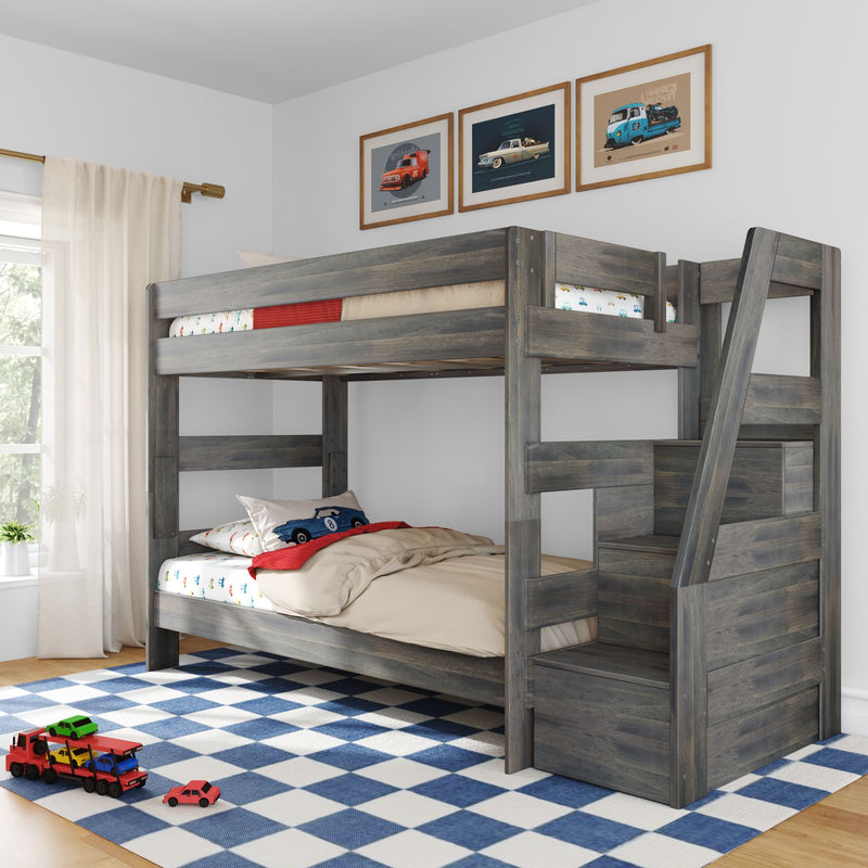 Gray wooden loft bunk bed with built-in stairs, car-themed bedding and framed car prints in a boys' bedroom with blue check rug