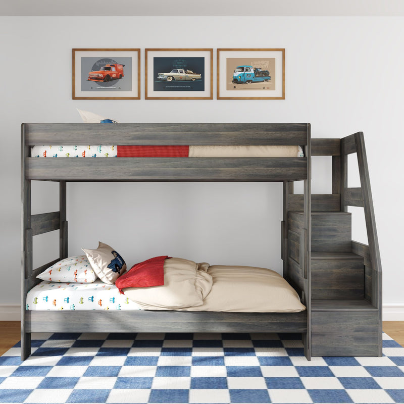 Gray wooden loft bunk bed with staircase storage in kids' bedroom, car-print bedding and pillow, red throw, framed vintage car wall art above and blue checkered rug
