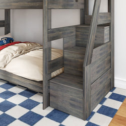 Gray rustic wooden twin-over-twin bunk bed with built-in storage stairs, beige bedding, blue checkered rug and toy car pillow in a kids' bedroom