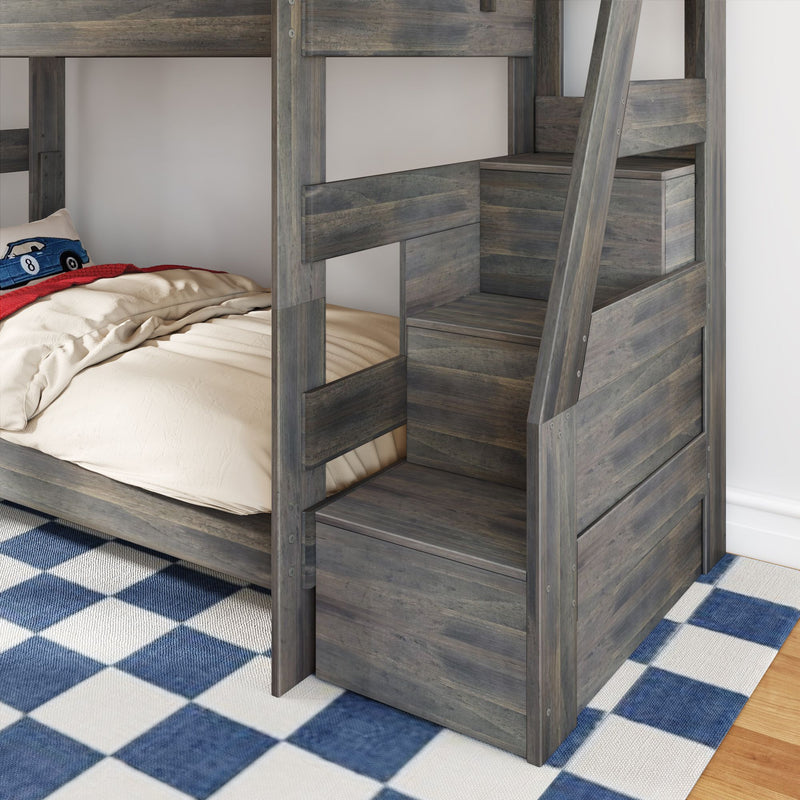 Gray rustic wooden twin-over-twin bunk bed with built-in storage stairs, beige bedding, blue checkered rug and toy car pillow in a kids' bedroom