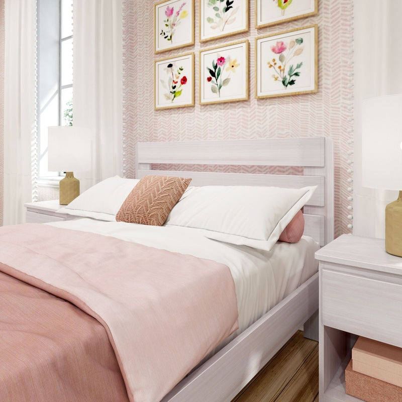 Cozy pink and white bedroom with white wood bed frame, soft pink bedding and textured throw pillow, matching nightstands with lamps, floral wall art and light wood flooring