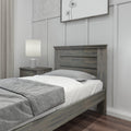Gray wood twin bed frame with slatted headboard and gray bedding in modern farmhouse bedroom with matching nightstand, lamp, and hardwood floor