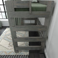Gray wooden loft bunk bed ladder and guardrail with green bedding, patterned area rug and window