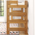Solid natural oak twin-over-twin bunk bed with sturdy guardrails in a bright modern farmhouse kids' bedroom with patterned rug