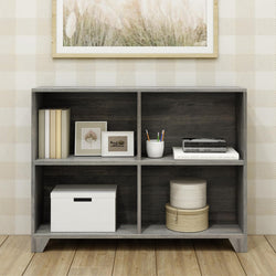 Modern gray bookshelf with decorative items including books, framed art, and storage boxes in a cozy room setting.