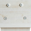Close-up of light pine wood panel with four recessed white hex-socket screws, countersunk furniture assembly and woodworking detail