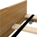 Close-up of wooden bed frame slats and center support with caster wheel and oak headboard detail