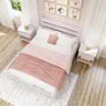 Boho chic pink and white bedroom interior with white wooden bed, soft pink bedding, textured rug, wood floors, nightstands with lamps and floral wall art