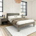 Cozy modern farmhouse bedroom interior with gray wood platform bed, neutral bedding, chevron-pattern accent wall, black-framed windows, bedside lamps and tasseled white rug