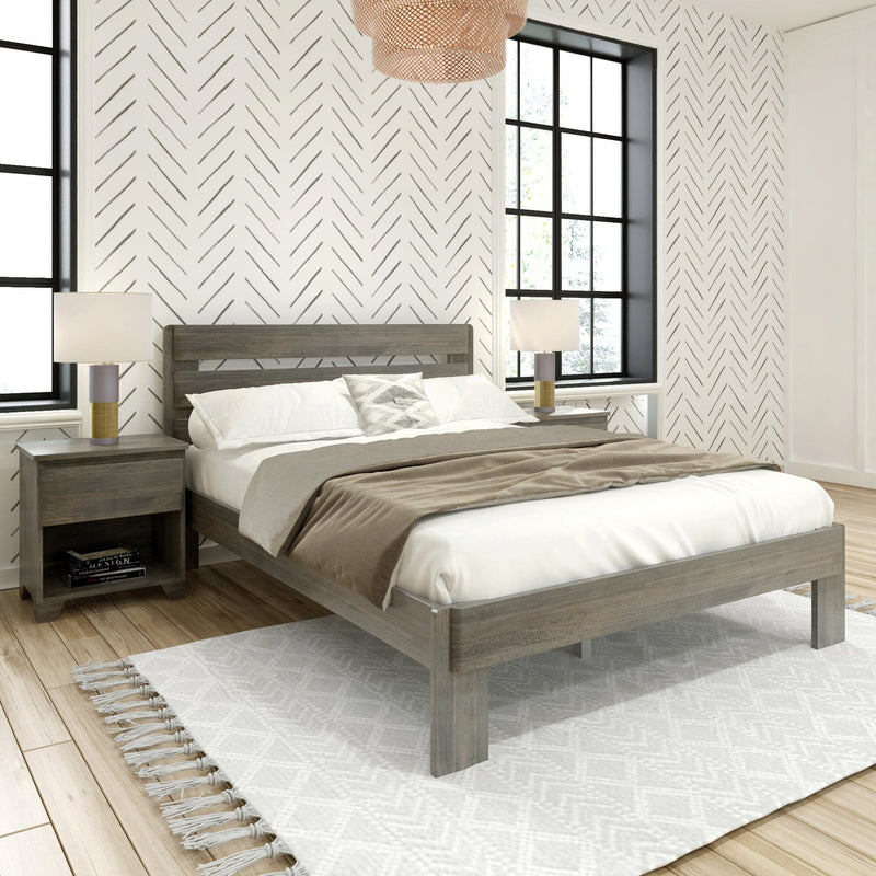 Cozy modern farmhouse bedroom interior with gray wood platform bed, neutral bedding, chevron-pattern accent wall, black-framed windows, bedside lamps and tasseled white rug