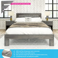 Grey solid wood platform bed with slatted headboard, matching nightstands and table lamps in a modern farmhouse bedroom with textured grey finish, patterned wallpaper and large windows