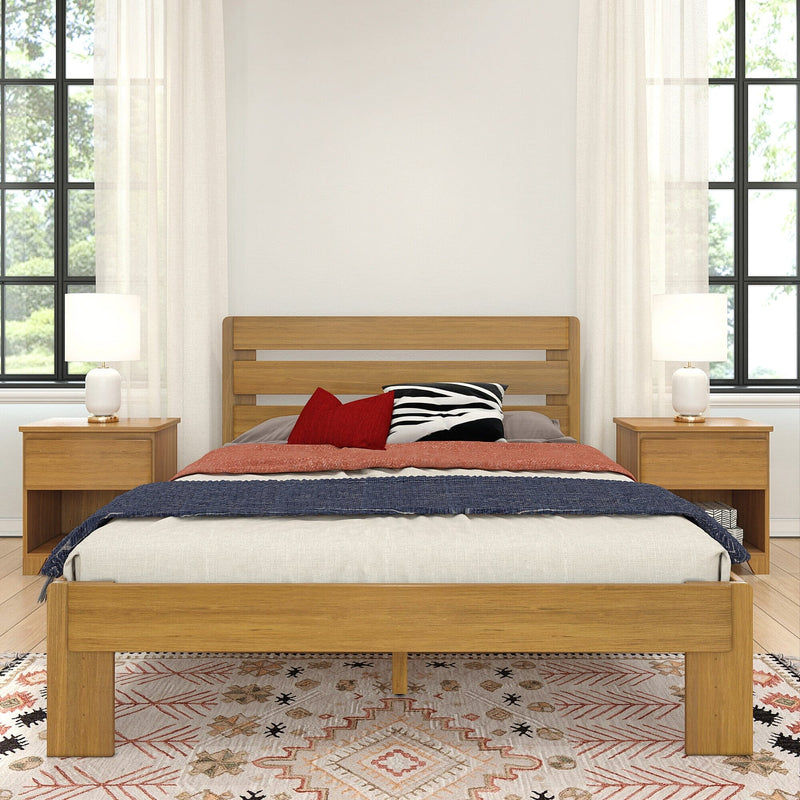 Modern bedroom with oak platform bed, matching nightstands and lamps, red and zebra accent pillows, sheer white curtains and patterned boho rug.