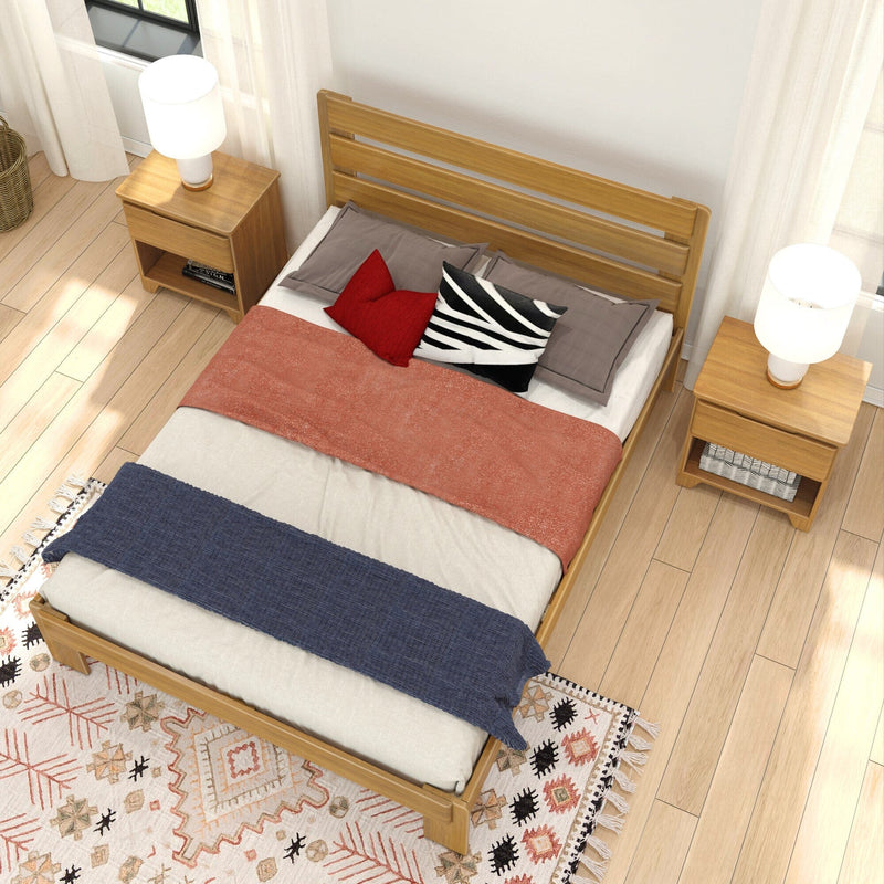 Aerial view of modern bedroom with wooden bed frame, matching nightstands and table lamps, decorative pillows, coral throw and boho rug on hardwood floor