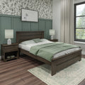 Modern farmhouse bedroom with dark wood platform bed, sage green bedding and throw, matching nightstands and lamps, green paneled accent wall with botanical wallpaper, wood flooring and patterned area rug
