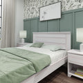 Modern bedroom with light wood bed, mint green bedding, board-and-batten sage accent wall, botanical wallpaper and bedside lamps