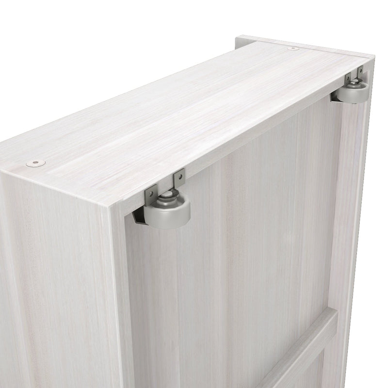 Close-up of whitewashed wooden sliding barn door top edge showing dual metal roller hardware and recessed mounting brackets