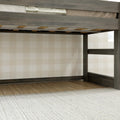 Gray wooden loft bed frame with slatted mattress support and ladder against beige buffalo-check wallpaper, hardwood floor and cream rug