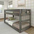 Rustic gray wooden twin-over-full bunk bed with guardrails and integrated ladder in a farmhouse-style neutral bedroom with plaid wallpaper and hardwood floor