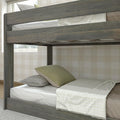 Rustic gray wooden twin bunk bed lower bunk with white mattress, green and gray pillows, light plaid throw and beige checkered wallpaper in a cozy kids' bedroom