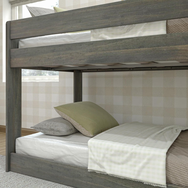 Rustic gray wooden twin bunk bed lower bunk with white mattress, green and gray pillows, light plaid throw and beige checkered wallpaper in a cozy kids' bedroom