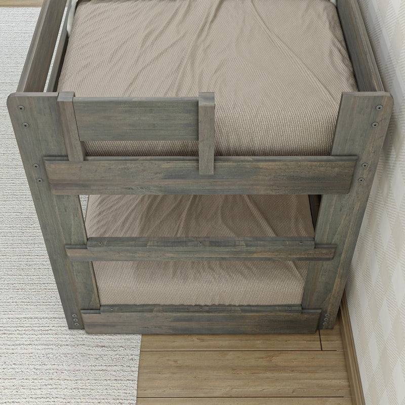 Top-down view of rustic gray wooden bunk bed safety guardrail with beige mattress and textured bedding on hardwood floor and rug