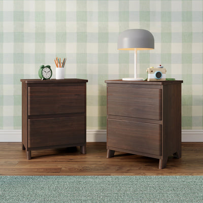 Dark wood nightstands with modern gray table lamp, green alarm clock, pencil holder and wooden toy camera against mint green gingham wallpaper — stylish bedroom/nursery decor